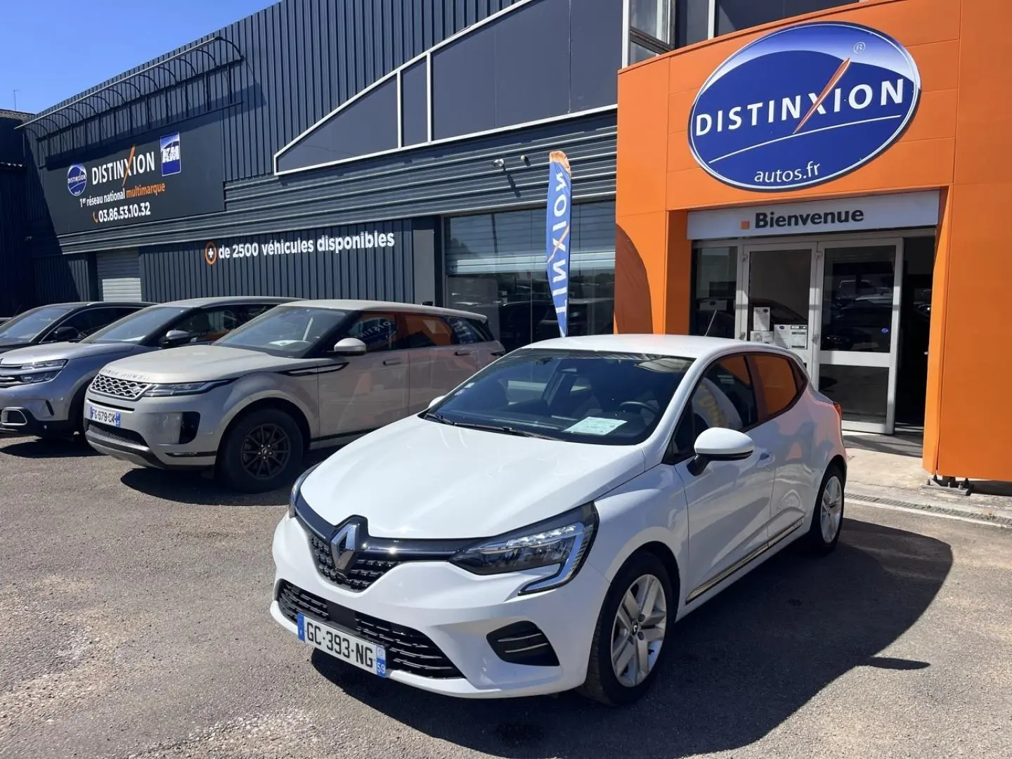 Renault Clio blanc Quartz vue 3/4 avant droit, garée devant un concessionnaire Distinxion.