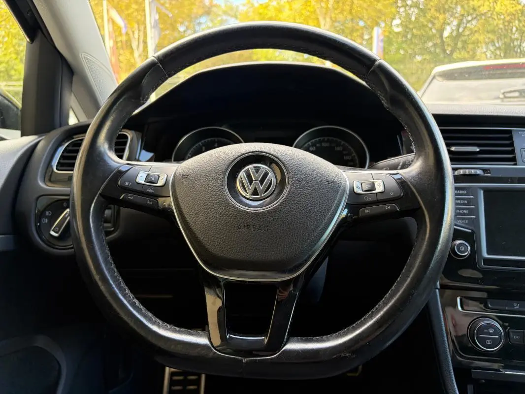 Vue rapprochée du volant cuir multifonctions noir d’une Volkswagen Golf 7, avec tableau de bord et console centrale visibles.