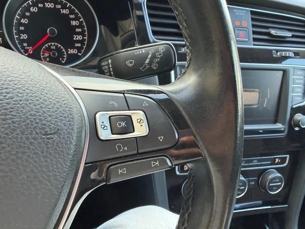 Gros plan sur le volant cuir multifonctions côté gauche d’une Volkswagen Golf 7 noire avec tableau de bord et commandes visibles.