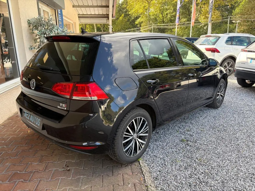 Vue 3/4 arrière droite d'une Volkswagen Golf 7 noire, avec jantes alliage et rétroviseurs électriques rabattables.