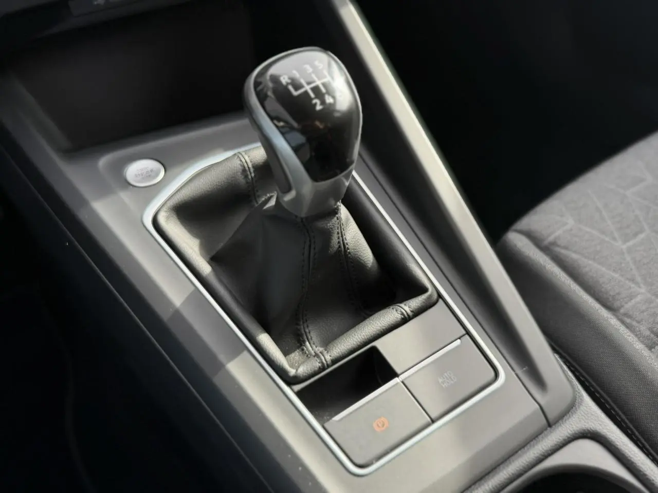 Gros plan sur le levier de vitesses manuel noir et gris dans la console centrale de la Volkswagen Golf 8 gris lunaire.