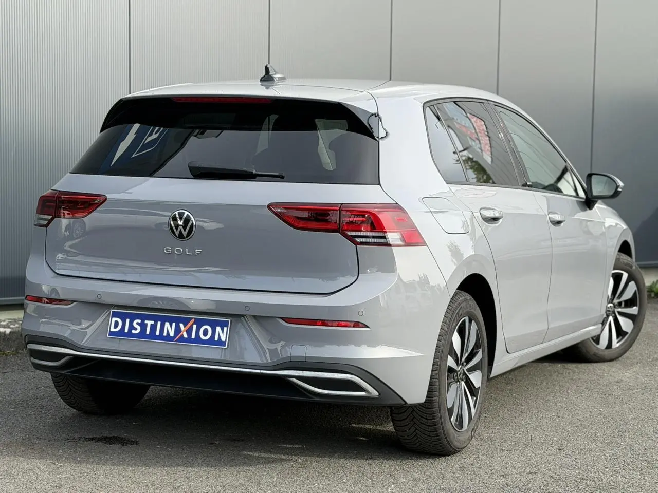 Volkswagen Golf 8 gris lunaire vue 3/4 arrière droit, feux LED et jantes alliage distinctives.
