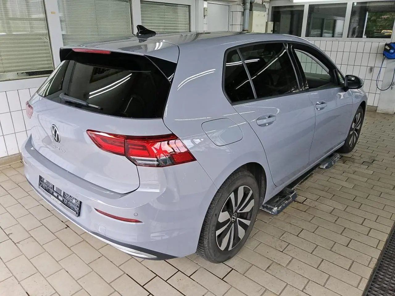 Vue 3/4 arrière droit d'une Volkswagen Golf 8 gris lunaire avec feux arrière LED et jantes alliage Norfolk.