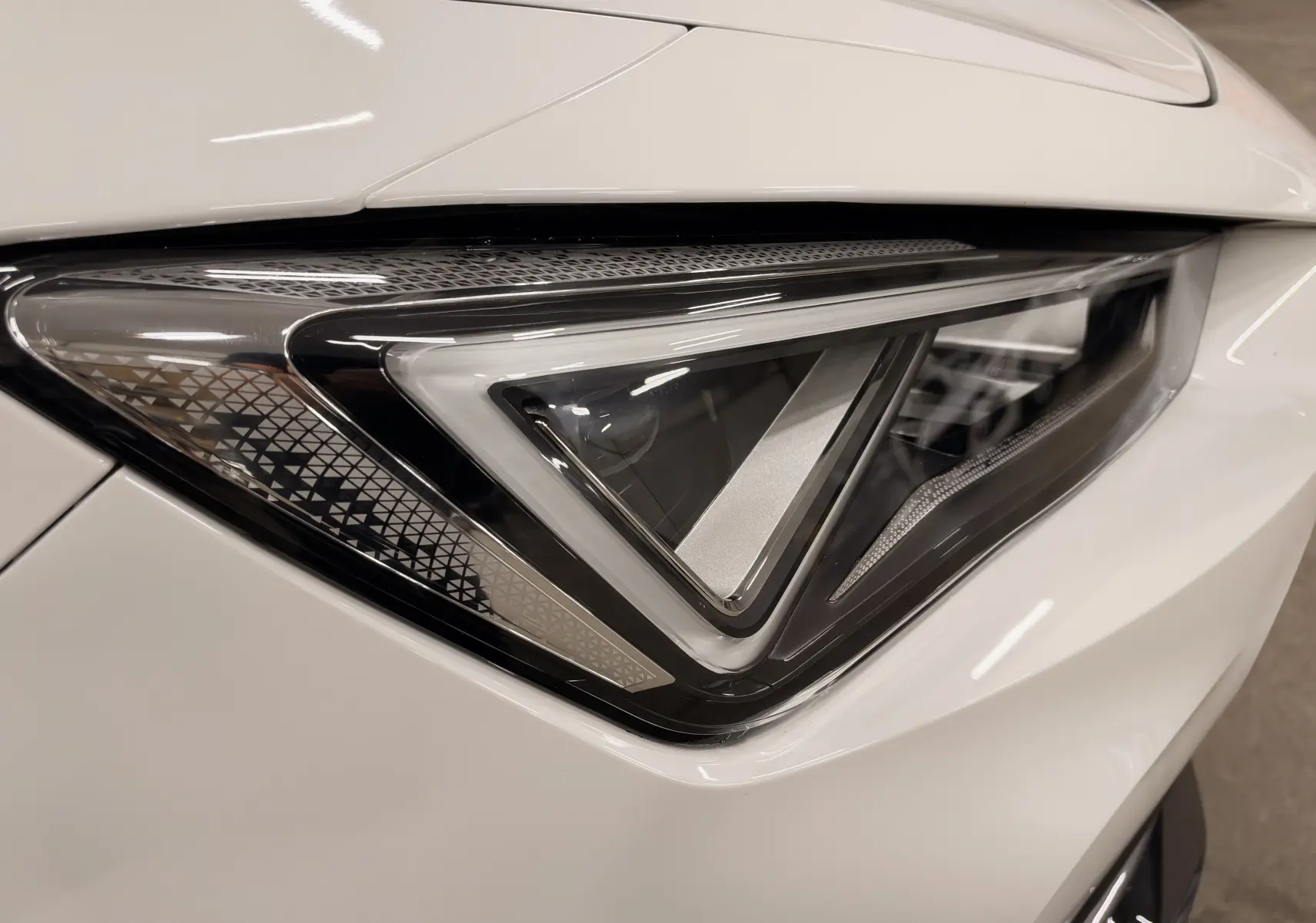 Gros plan sur le phare avant droit blanc du CUPRA Formentor 1.4 E-HYBRID 245 CH VZ DSG6 2024, design triangulaire distinctif.