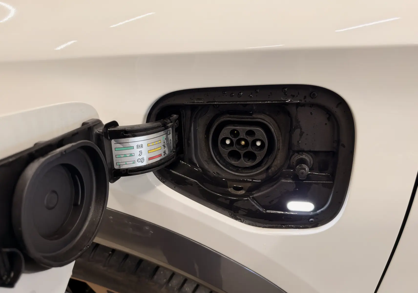 Prise de recharge ouverte côté gauche sur CUPRA Formentor blanc, montrant le connecteur électrique hybride.