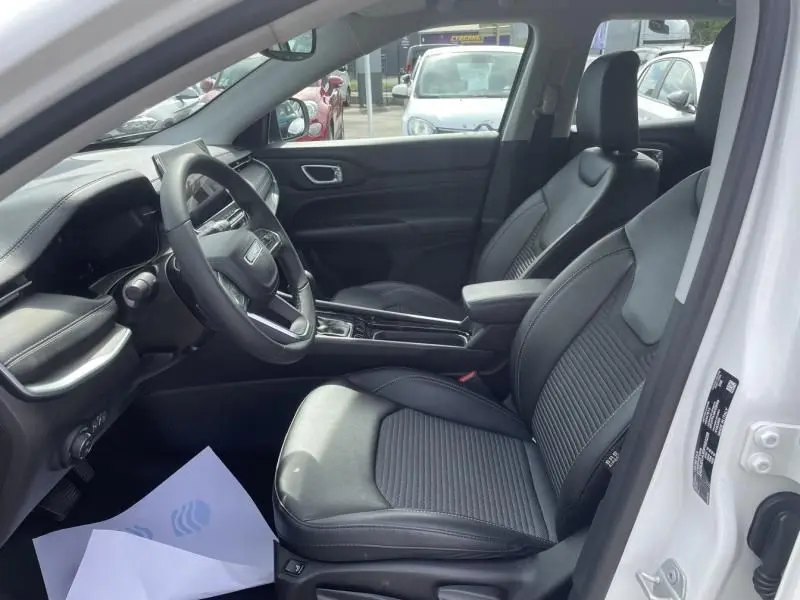 Intérieur du Jeep Compass 2024 blanc, vue côté gauche, sièges noirs en cuir et tableau de bord moderne.