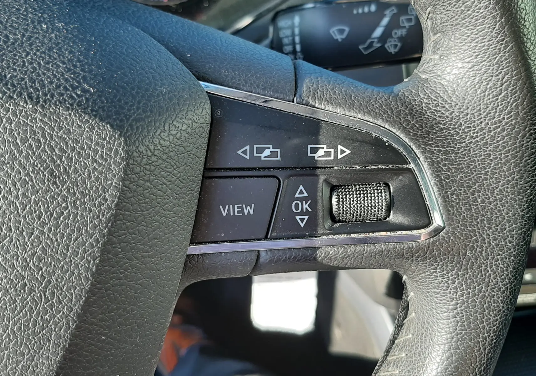 Gros plan sur les commandes à gauche du volant en cuir noir du SEAT Arona gris Magnetic 2019.