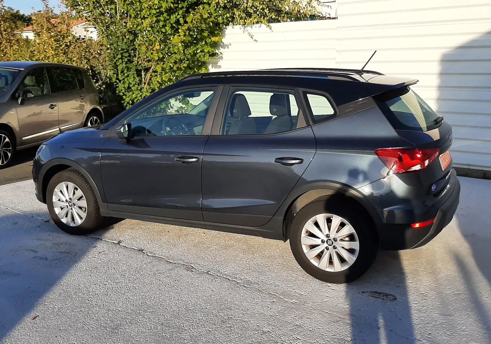 SEAT Arona gris magnetic avec toit noir, vue profil côté gauche, garée en extérieur au soleil.