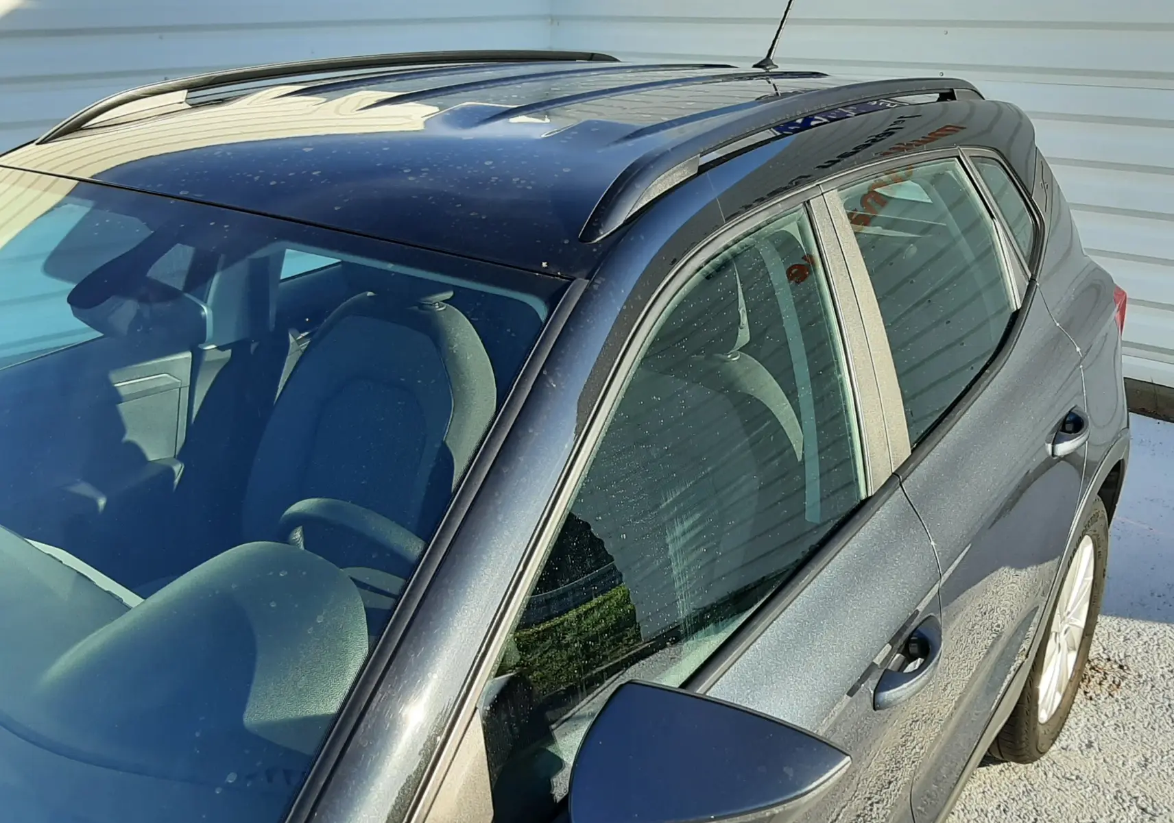 Vue de dessus côté droit d'un SEAT Arona gris magnetic avec toit noir et barres de toit visibles.