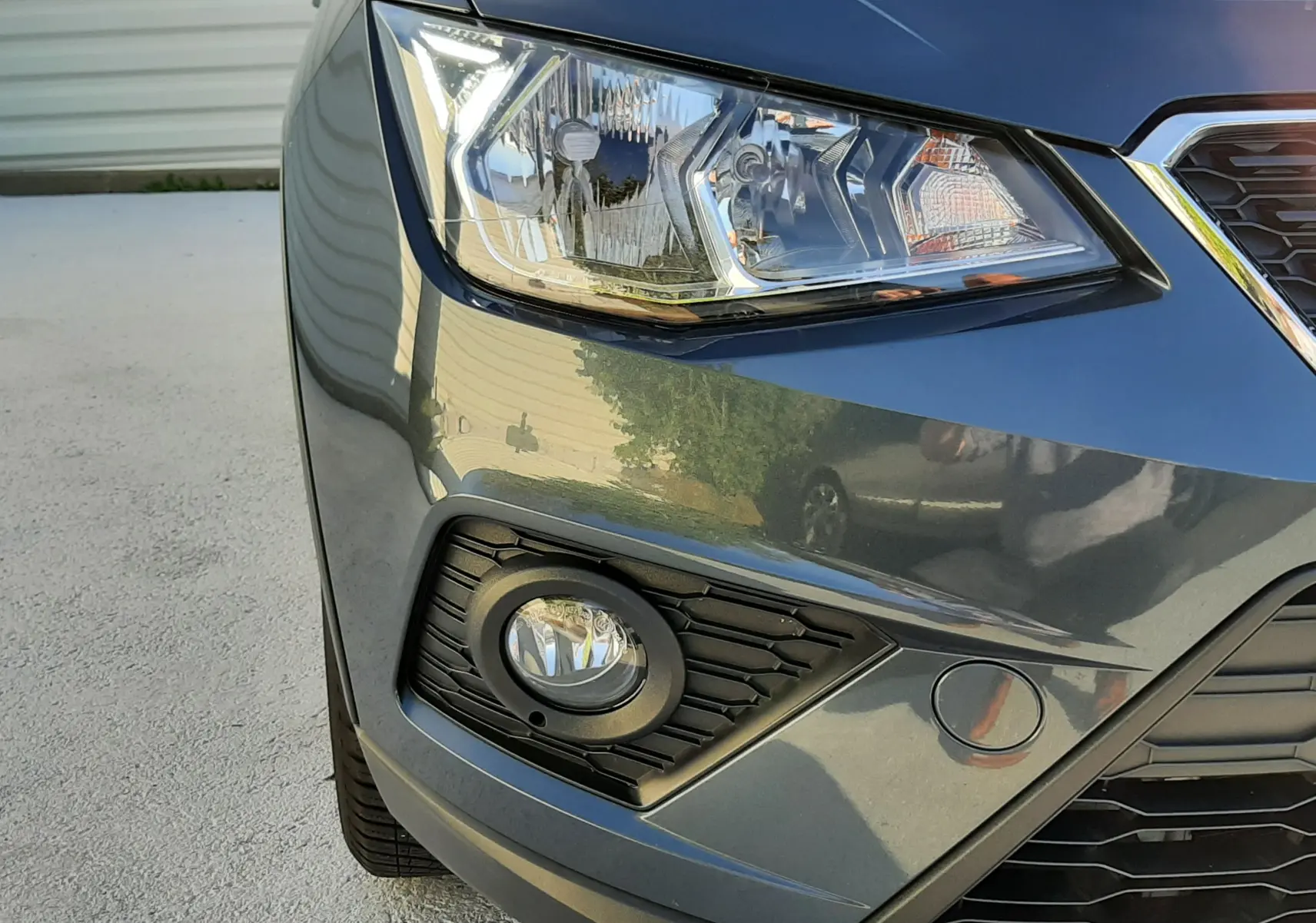 Gros plan sur l'avant droit d'une SEAT Arona gris magnetic avec phare et antibrouillard visibles.
