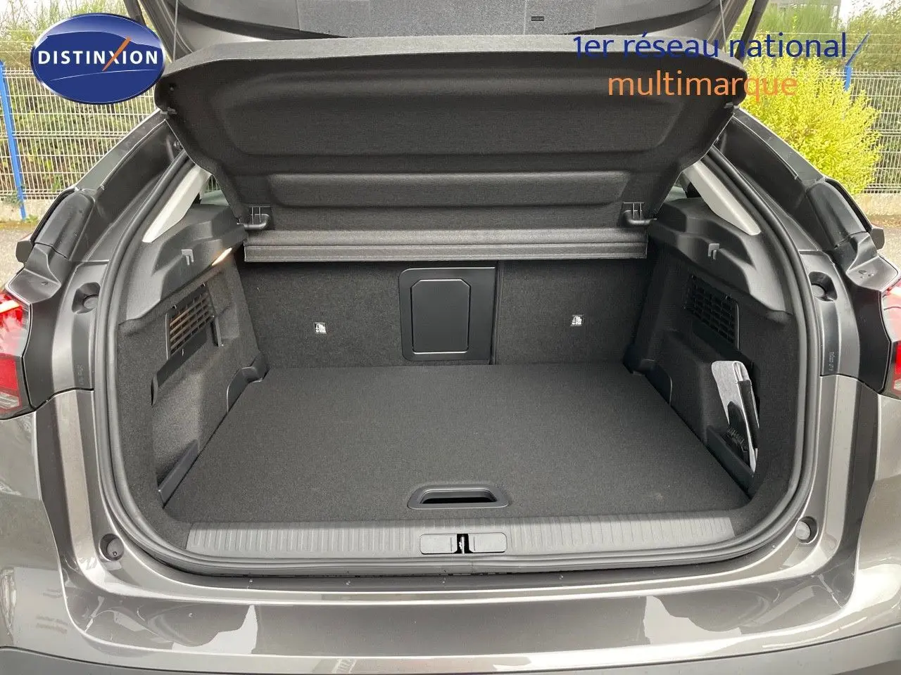 Coffre ouvert vu de l'arrière d'une Citroën C4 2024 gris platinium métal, montrant un espace de chargement spacieux et propre.