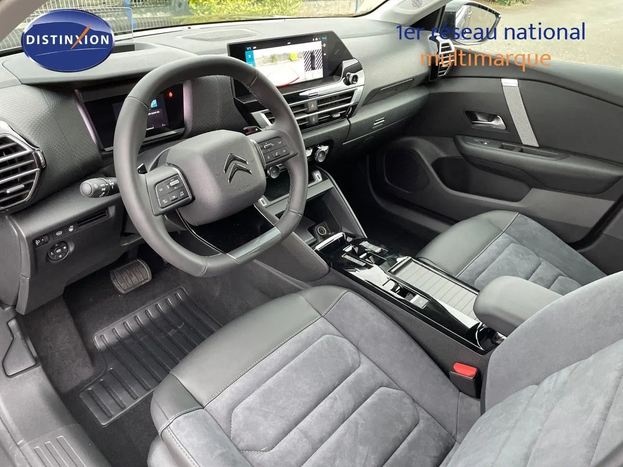Intérieur moderne de la Citroën C4 2024, vue côté conducteur, sièges en cuir noir et alcantara gris, tableau de bord avec écran tactile.