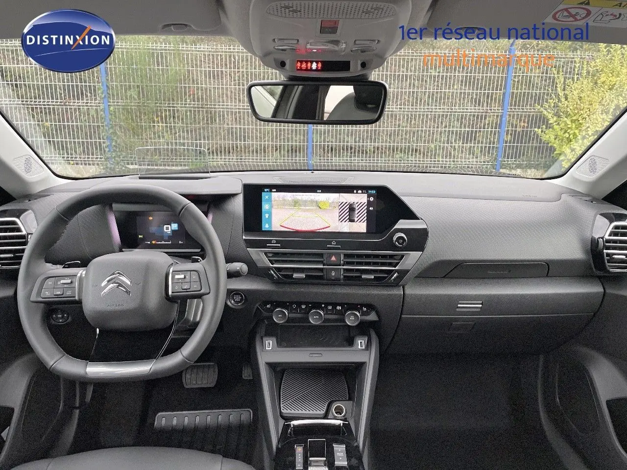 Vue intérieure avant du tableau de bord et volant noir de la Citroën C4 2024 avec écran tactile affichant la caméra de recul.