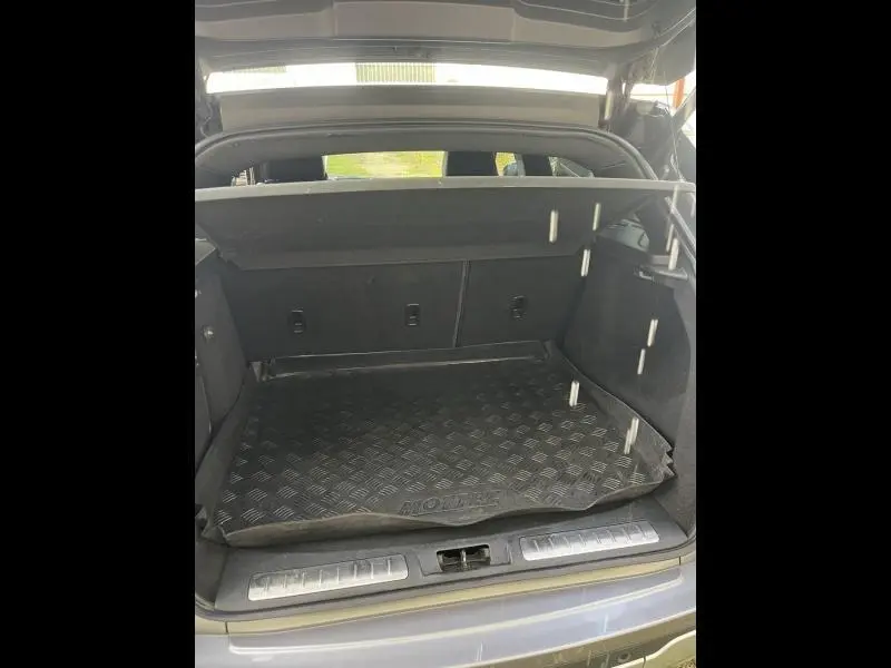 Coffre ouvert vu de l'arrière d'un Range Rover Evoque gris Orkney avec tapis de sol noir et cache-bagages.
