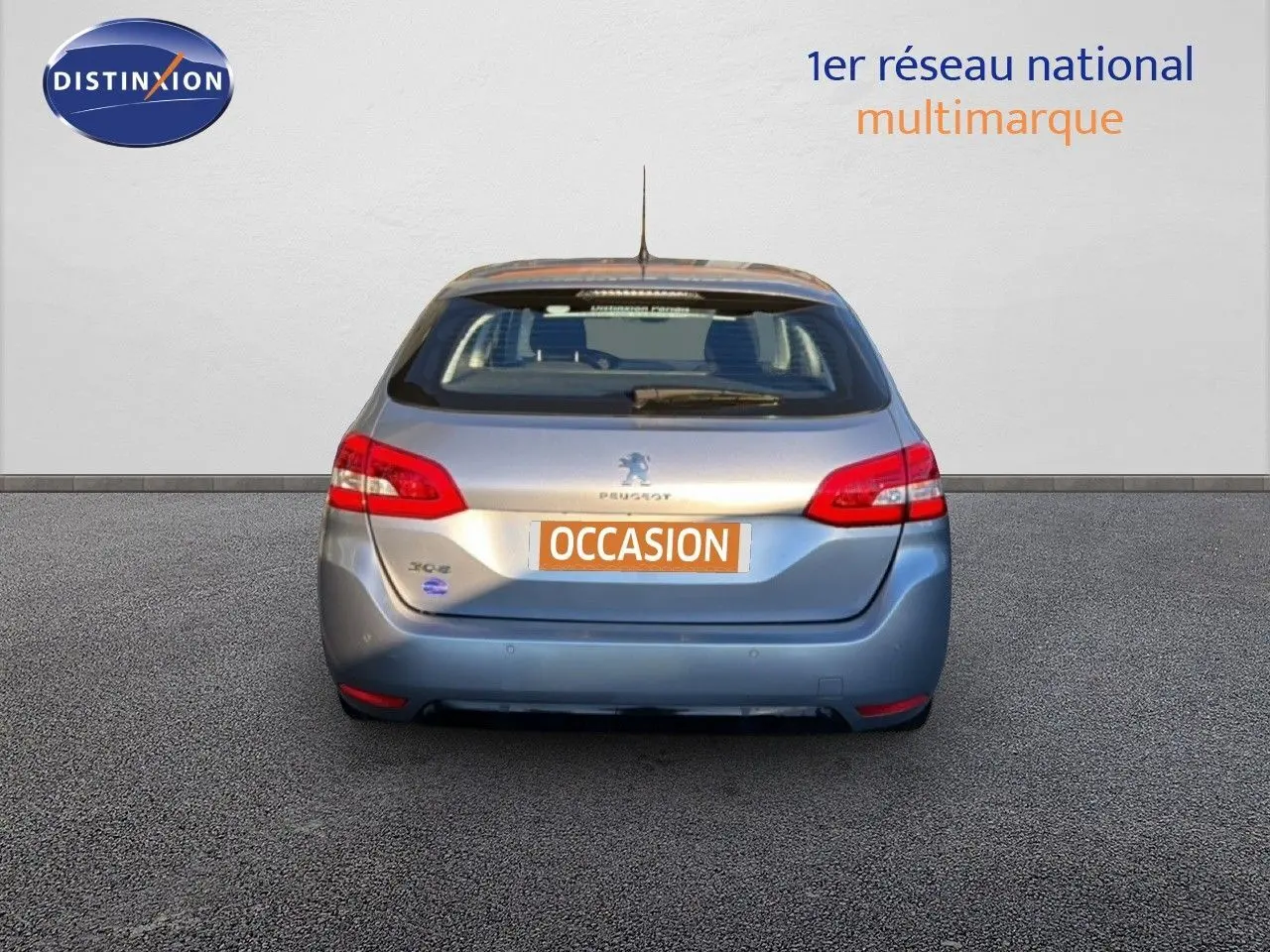Vue arrière d'une Peugeot 308 SW gris Artense métal de 2019 avec feux rouges et plaque "OCCASION" visible.