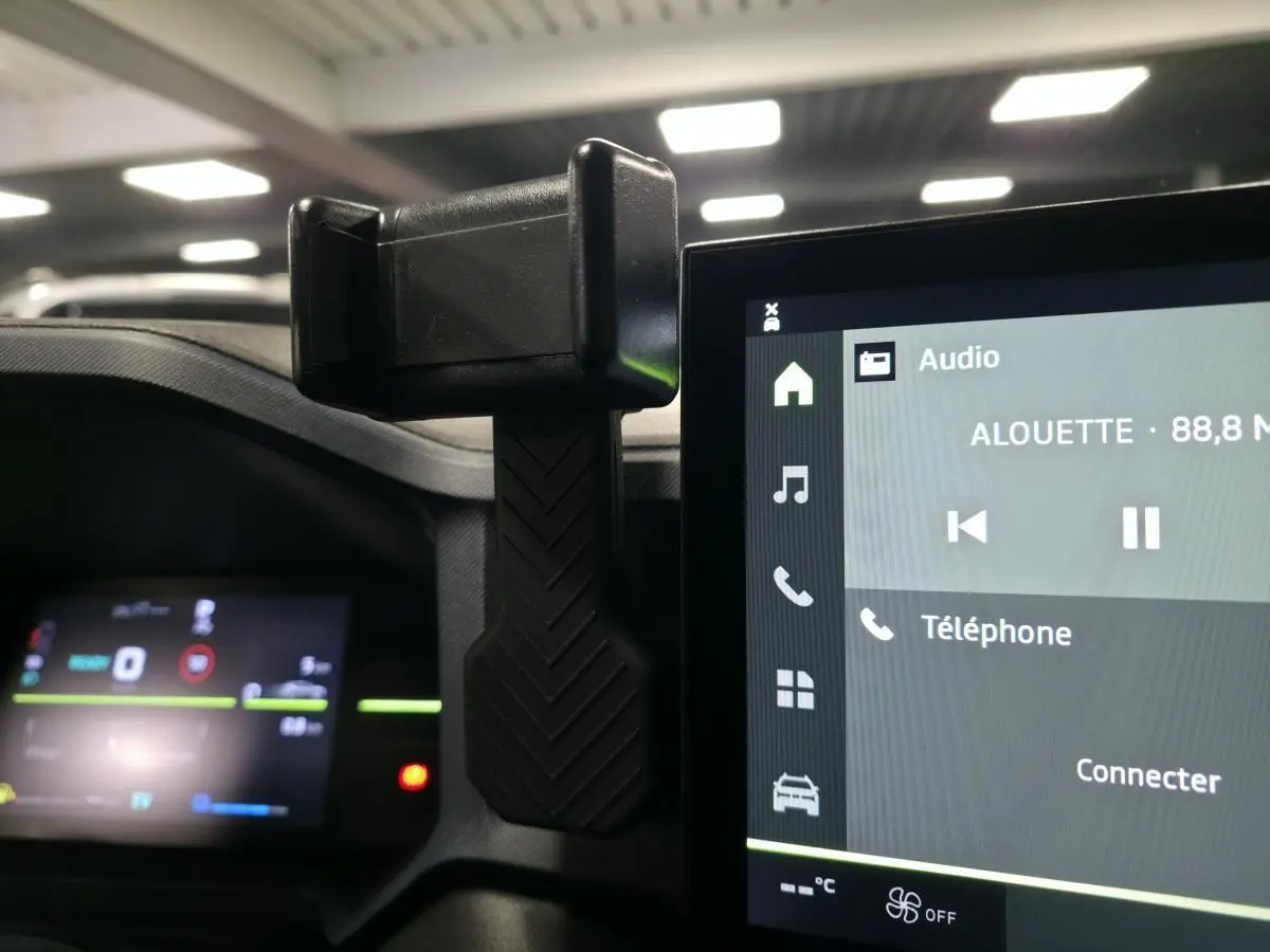 Vue intérieure du tableau de bord du Dacia Duster 2025 avec support smartphone et écran tactile multimédia.