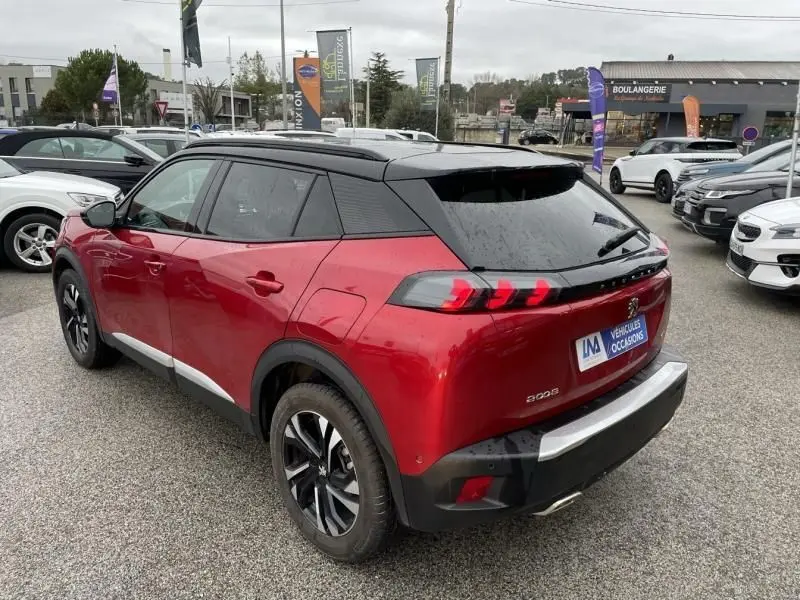 Peugeot 2008 130 GT-LINE rouge métal vue 3/4 arrière droit, toit noir et feux arrière à griffes distinctifs.