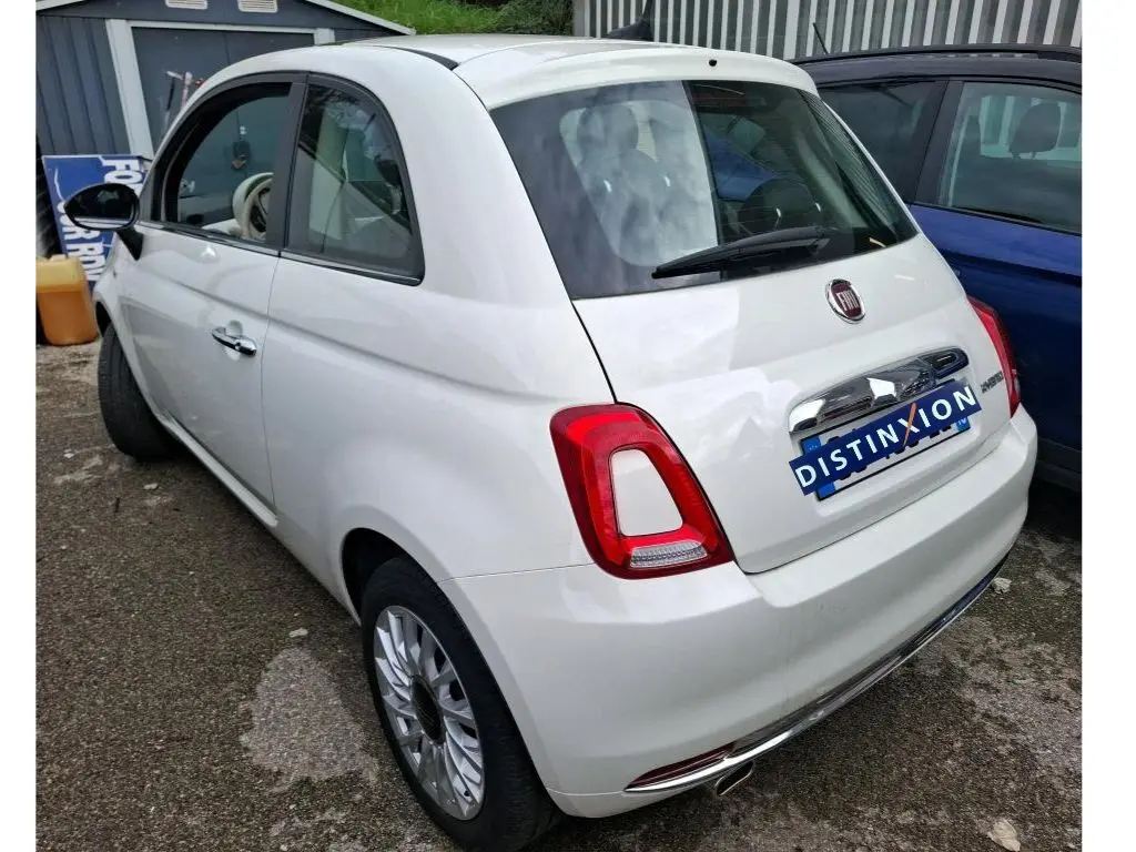 Vue 3/4 arrière droite d'une FIAT 500 blanche Bossa Nova, avec feux arrière rouges et jantes alliage multibranches.