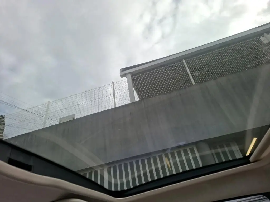 Toit ouvrant panoramique visible depuis l'intérieur d'une FIAT 500 blanche Bossa Nova, vue vers le ciel nuageux.