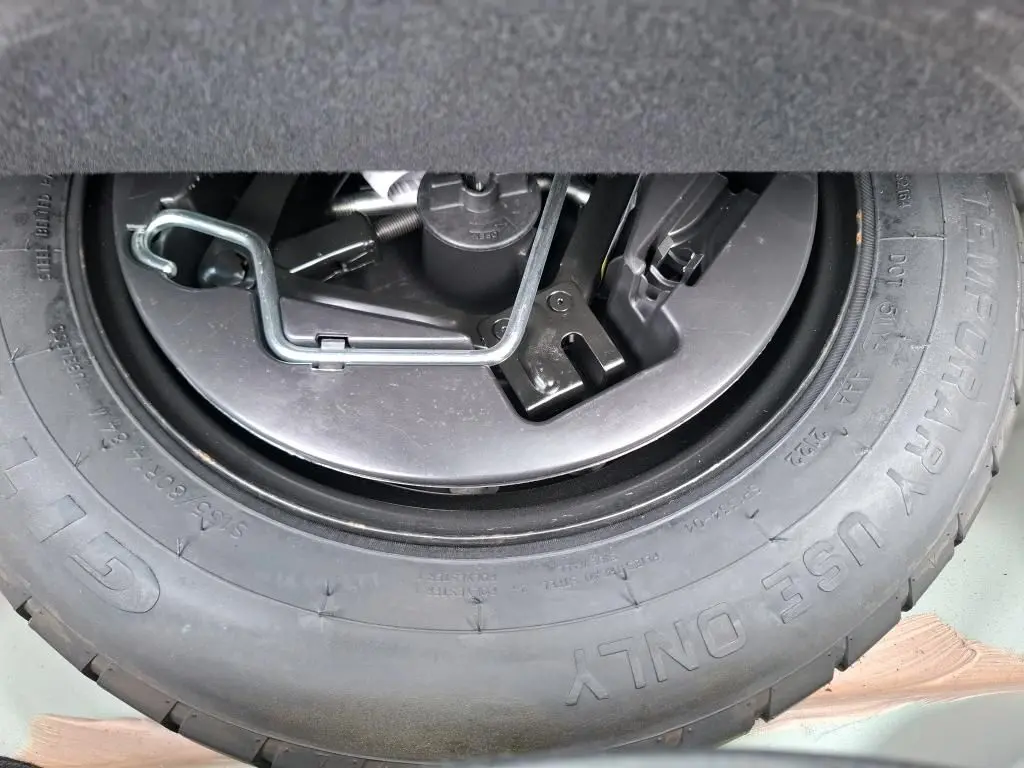 Gros plan sur la roue de secours et les outils de bord du coffre d'une FIAT 500 blanche Bossa Nova 2022.