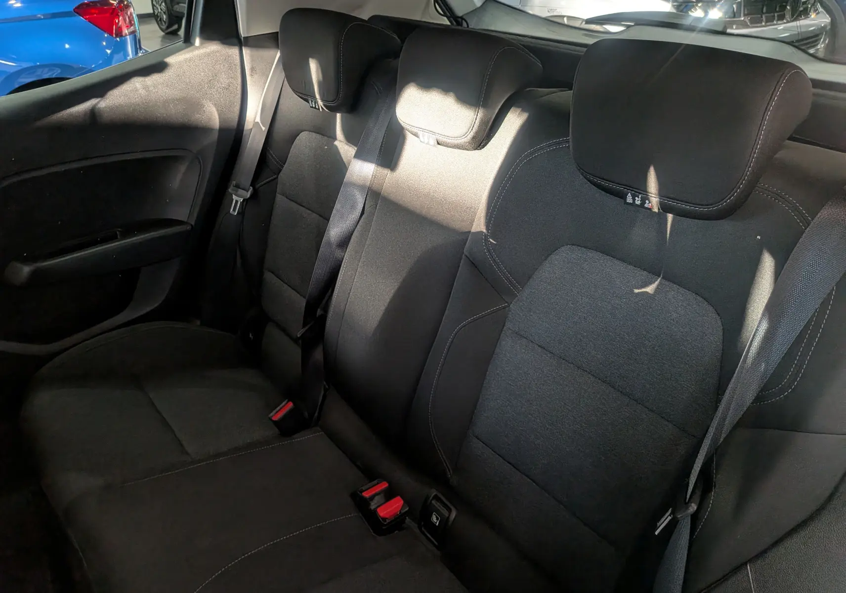 Vue intérieure sur la banquette arrière en tissu noir de la Renault Clio V Business, avec ceintures et appuie-têtes visibles.