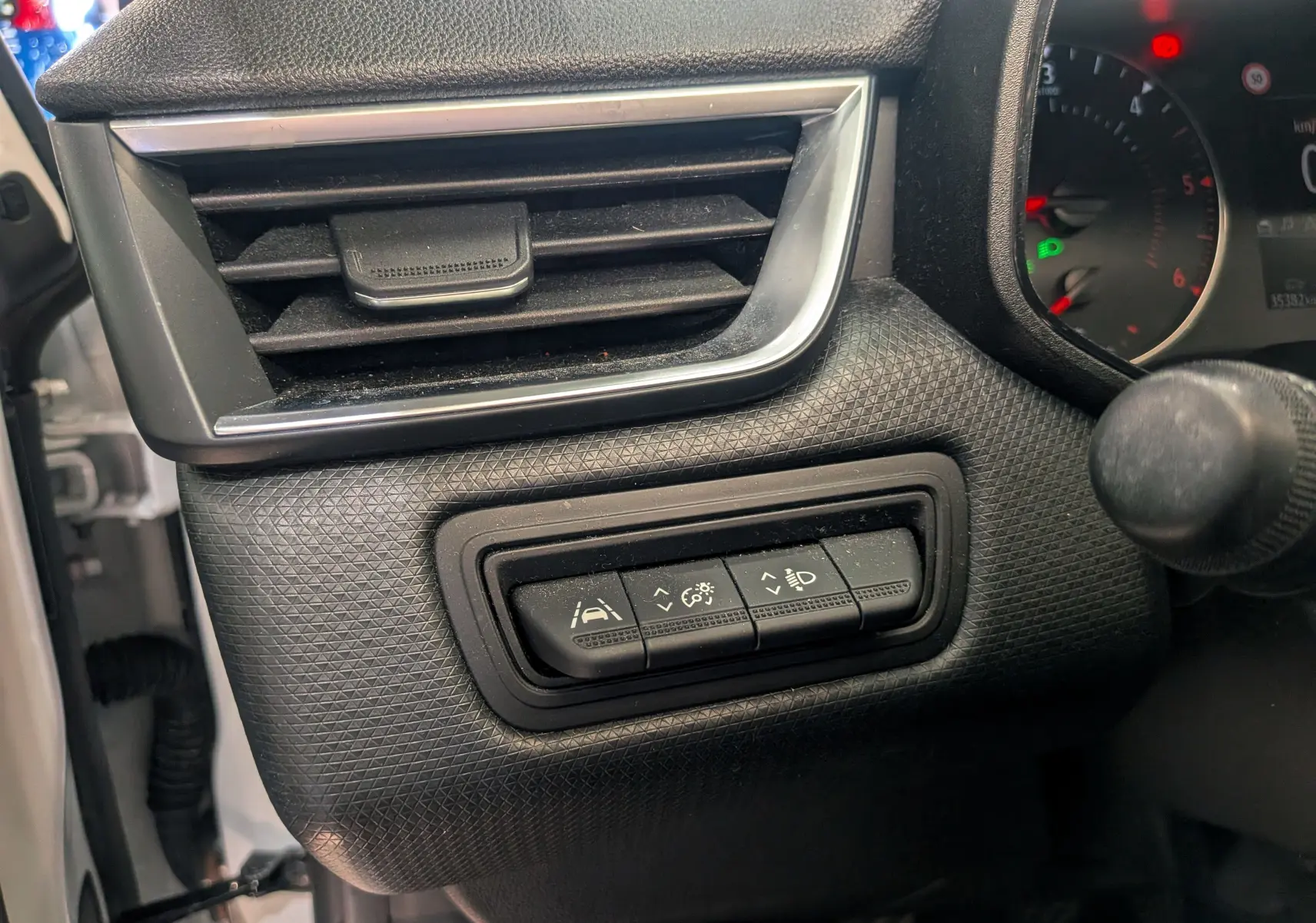 Détail intérieur du tableau de bord côté gauche de la Renault Clio V blanc glacier, avec commandes d'assistance et ventilation.