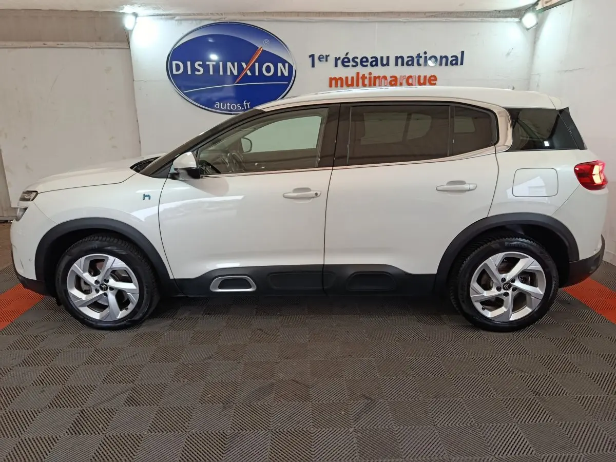 Profil droit d'un Citroën C5 Aircross Hybrid blanc, avec détails noirs contrastants et jantes alliage cinq branches.