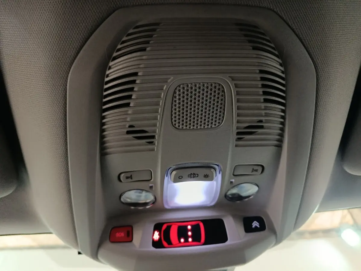 Vue intérieure du plafonnier gris avec éclairage, boutons SOS et commande d'ouverture du toit ouvrant du Citroën C5 Aircross blanc.