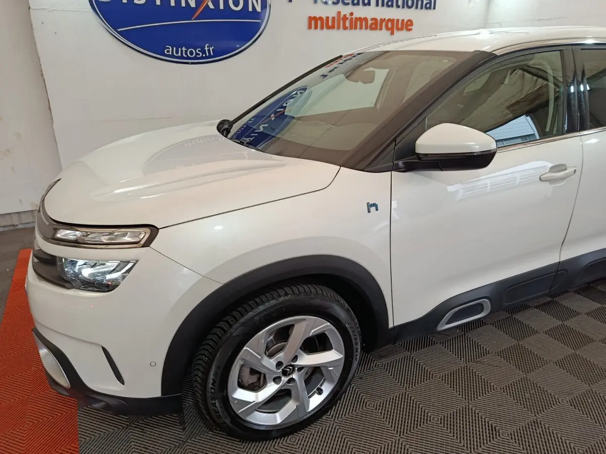 Vue 3/4 avant droit d'une Citroën C5 Aircross Hybrid blanche avec jantes alliage et détails noirs contrastants.