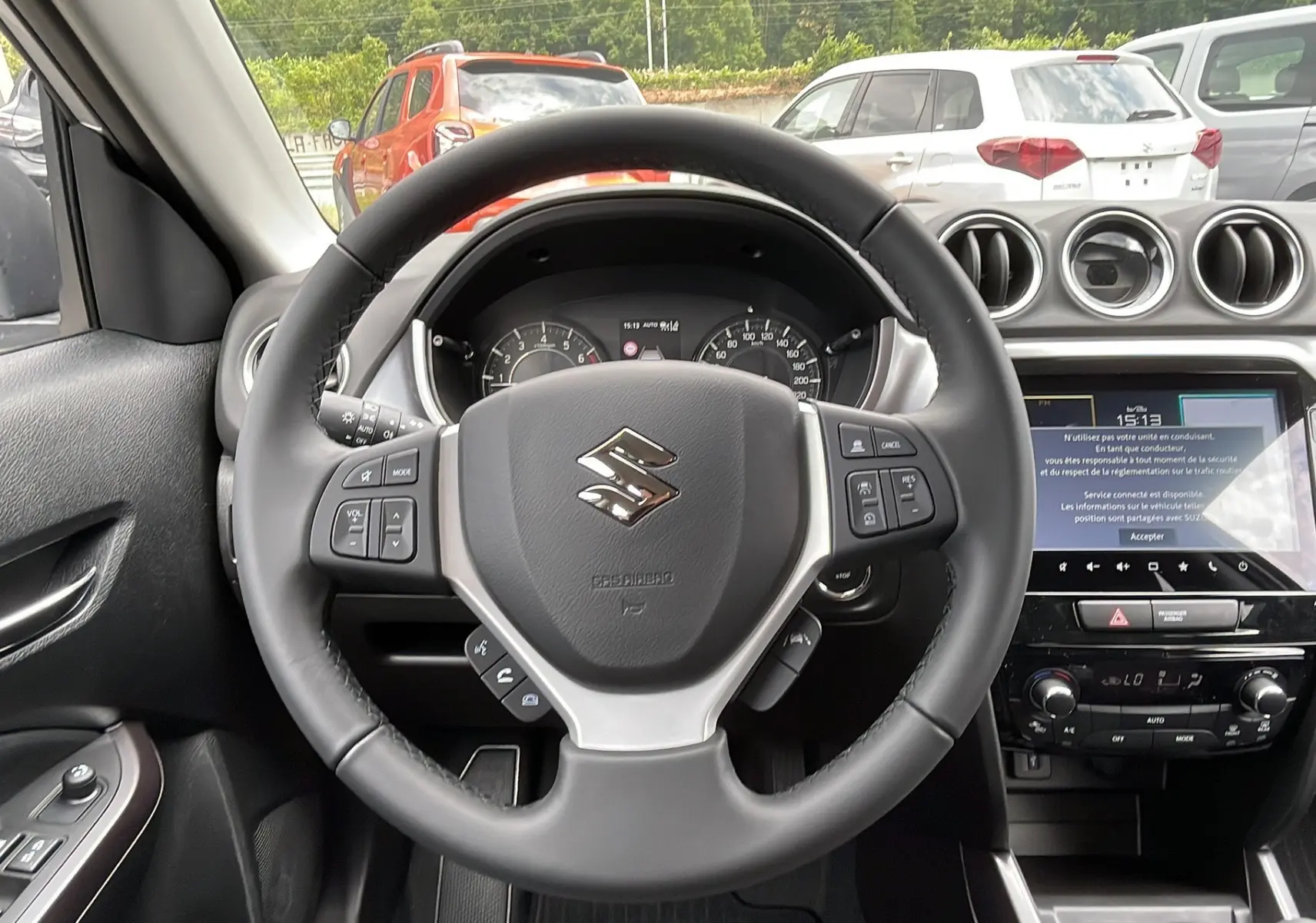 Vue intérieure centrée sur le volant cuir multifonctions du Suzuki Vitara 2025, avec écran tactile et commandes au tableau de bord.