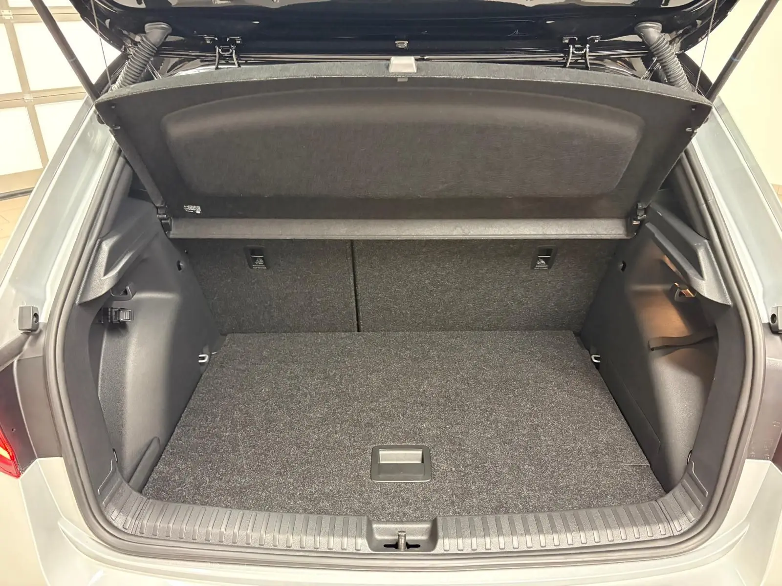 Coffre ouvert vu de l'arrière d'une Skoda Fabia 2025 gris argent avec toit noir, montrant le double plancher variable.