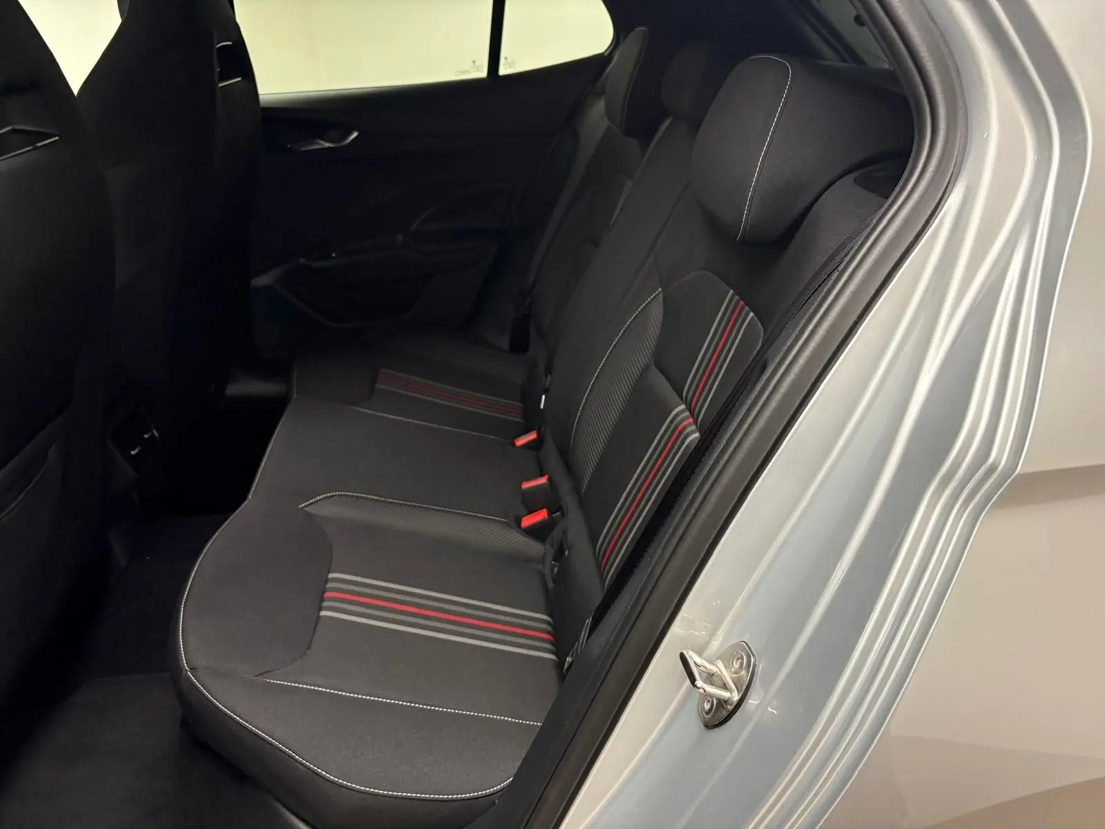 Vue intérieure côté droit des sièges arrière noirs avec surpiqûres blanches et bandes rouges sur une Skoda Fabia gris argent 2025.