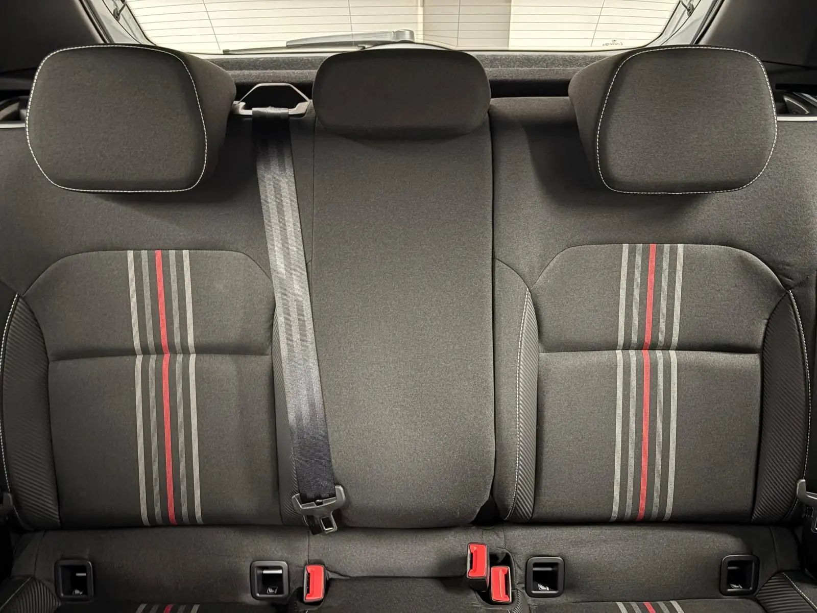 Vue intérieure des sièges arrière de la Skoda Fabia 2025, tissu gris avec bandes rouges et grises centrales.