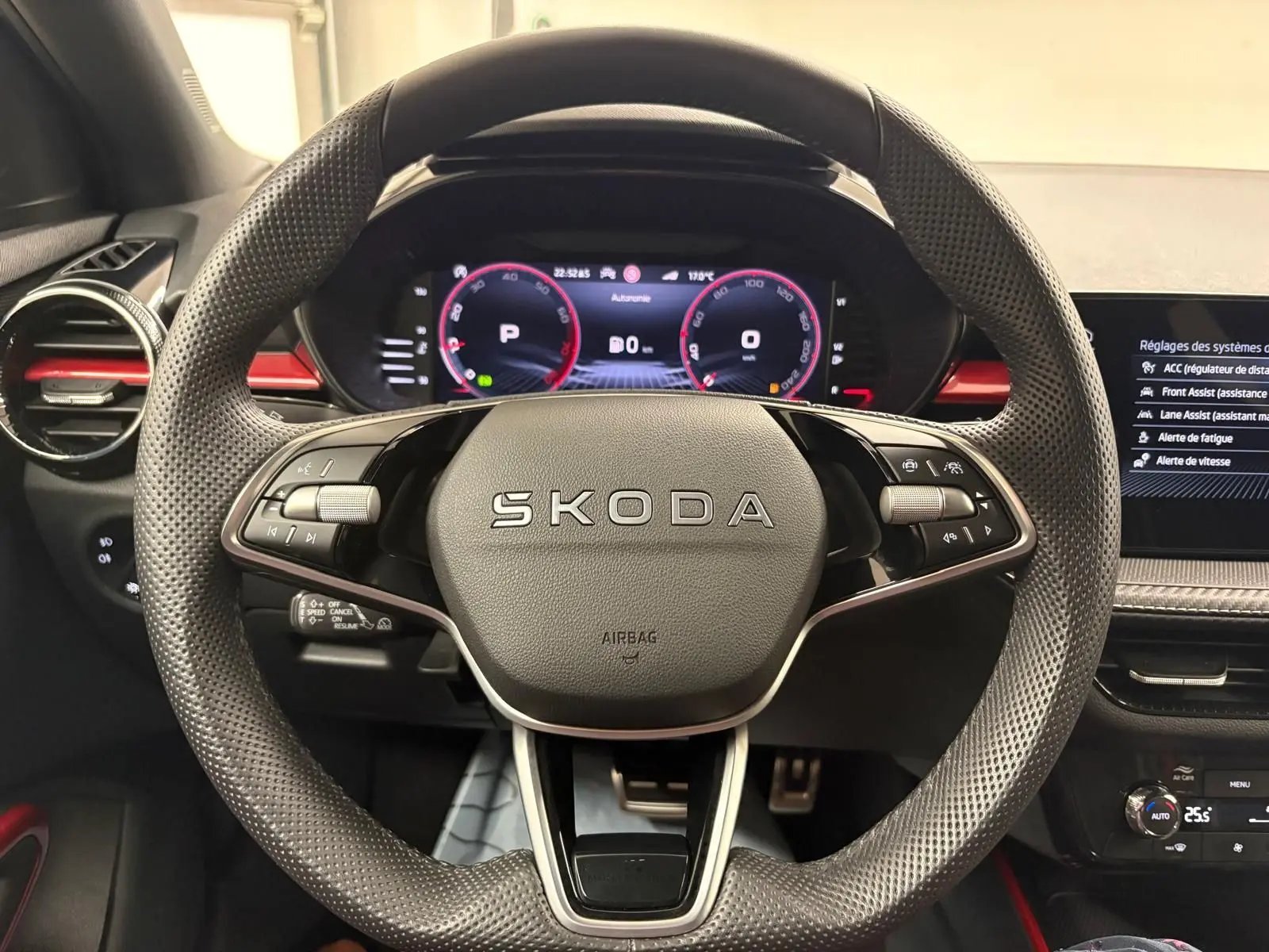 Vue centrée sur le volant perforé SKODA de la Fabia 2025 avec tableau de bord numérique et inserts rouges.