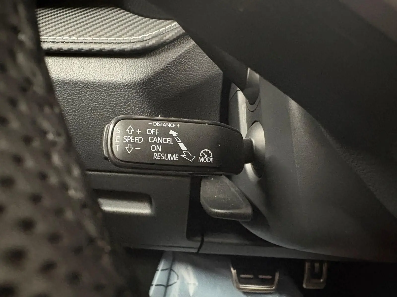 Gros plan sur la commande du régulateur de vitesse adaptatif dans une Skoda Fabia 2025, intérieur noir.