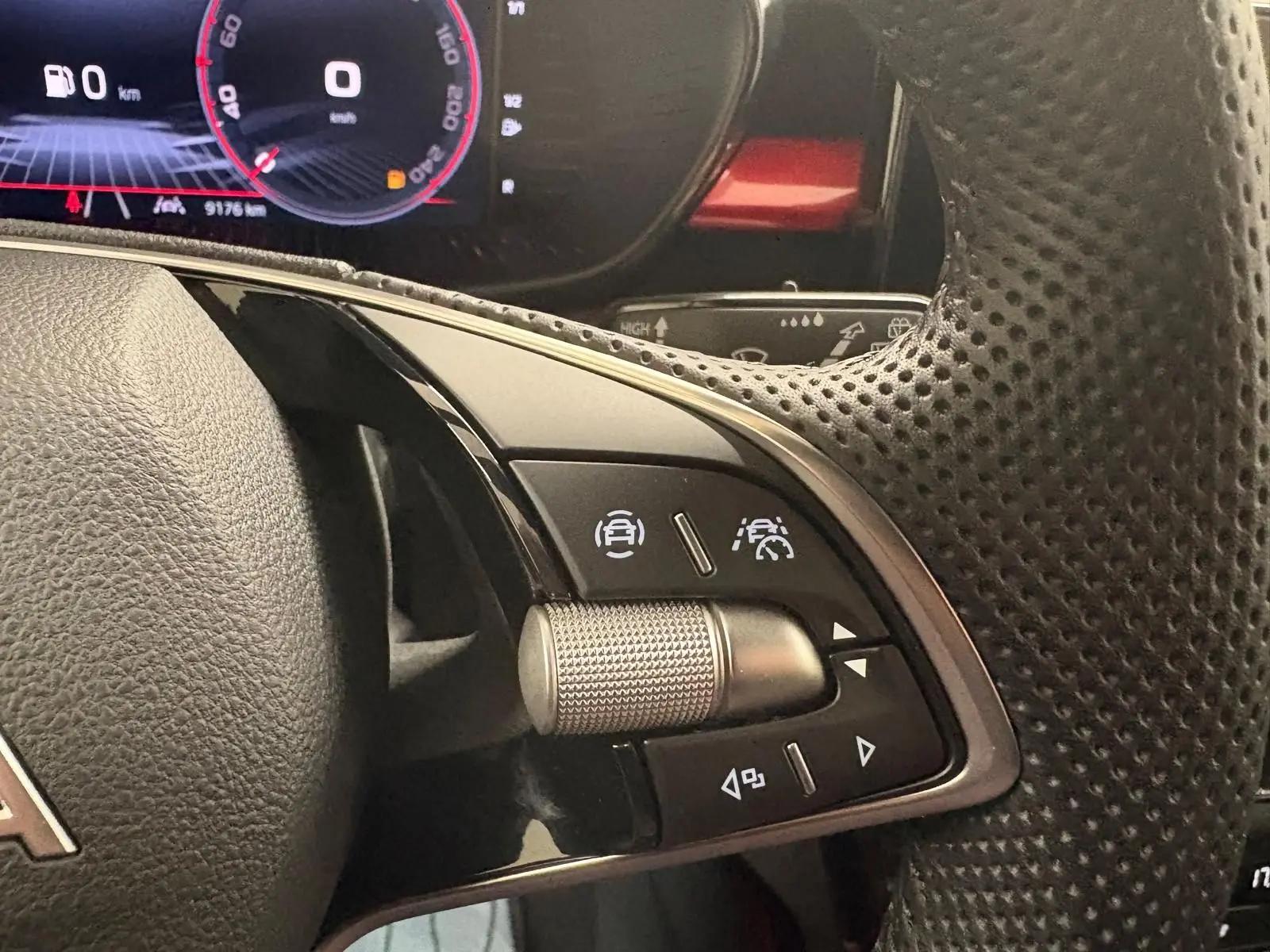 Gros plan sur les commandes au volant perforé de la Skoda Fabia 1.0 TSI 116 DSG7 Monte Carlo, tableau de bord numérique visible.