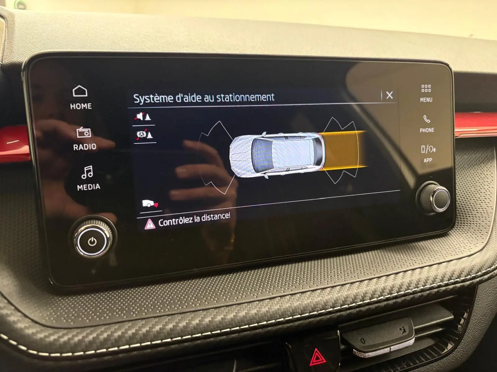Écran tactile du système d'aide au stationnement dans une Skoda Fabia 2025, tableau de bord noir avec surpiqûres blanches.