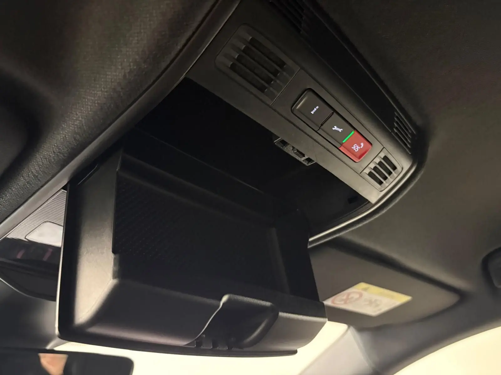 Gros plan sur le rangement plafond ouvert avec boutons SOS et assistance dans l’habitacle noir de la Skoda Fabia 2025.