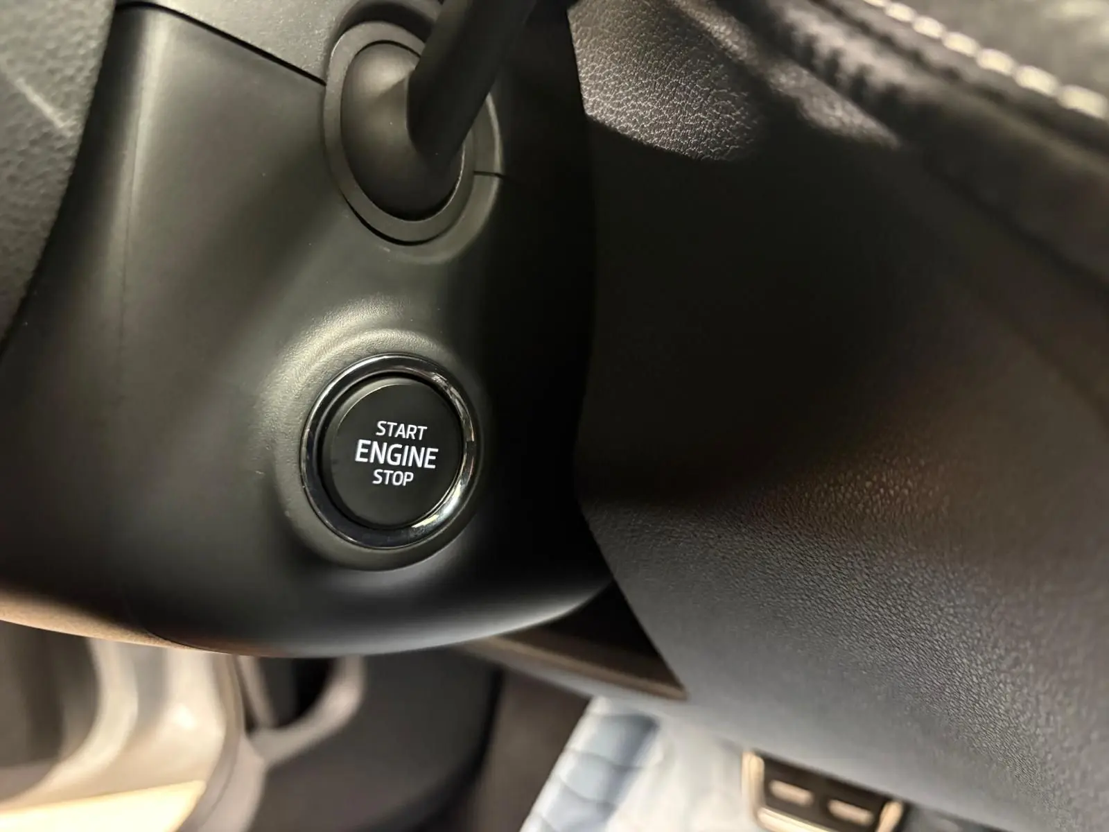 Gros plan sur le bouton Start Engine Stop du tableau de bord d'une Skoda Fabia 2025, intérieur noir.