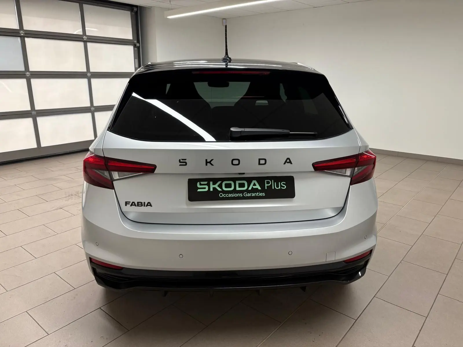 Vue arrière d'une Skoda Fabia 2025 gris argent avec toit noir, feux arrière LED et logo SKODA bien visible.