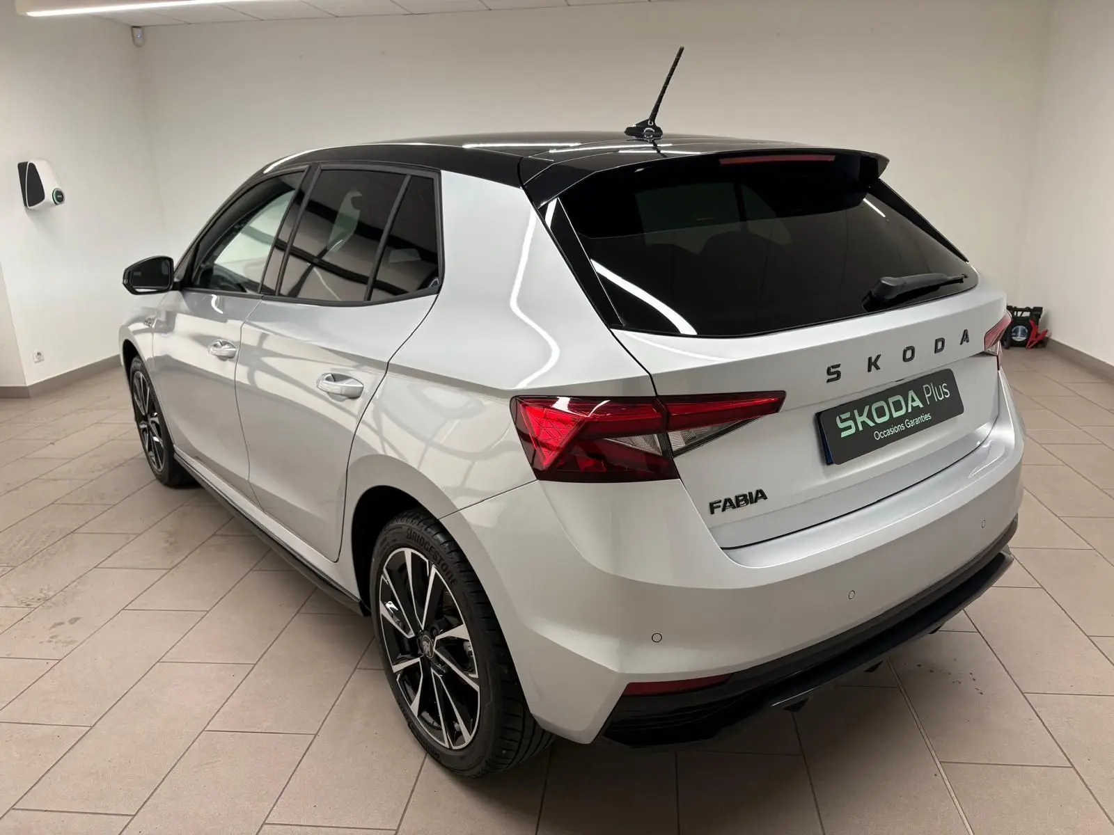 Vue 3/4 arrière droite d'une Skoda Fabia 2025 gris argent avec toit noir et jantes alliage noires.