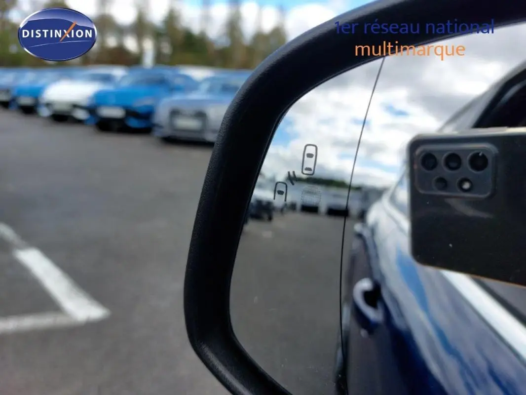 Rétroviseur droit d’une Ford Focus SW bleu foncé, avec plusieurs véhicules flous en arrière-plan.