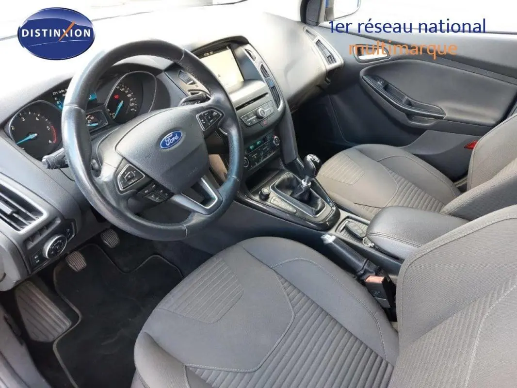 Vue intérieure avant droite de la Ford Focus SW 2018, montrant le volant, la console centrale et les sièges gris.