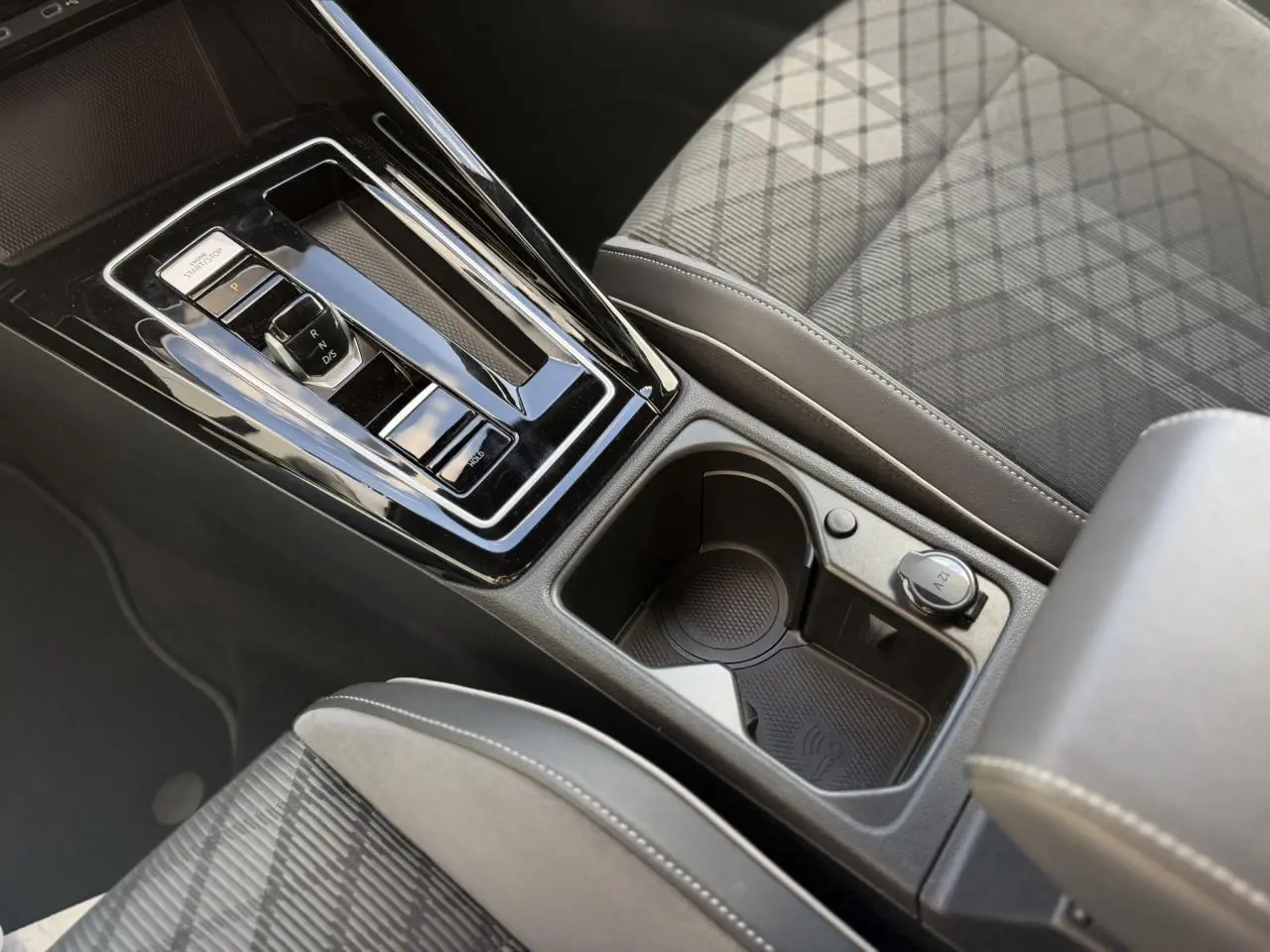 Gros plan sur la console centrale noire de la Volkswagen Golf 8 R-Line 2024 avec levier de vitesse et porte-gobelets.