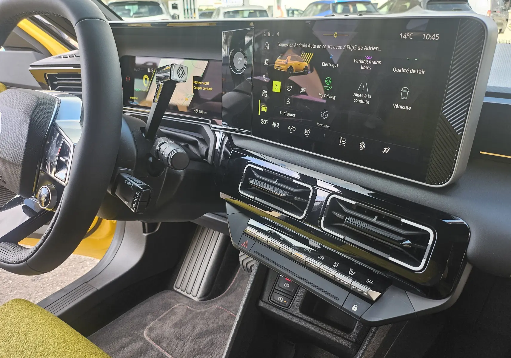 Vue intérieure côté conducteur de la Renault R5 Iconic 150 électrique jaune pop, avec tableau de bord numérique et écran tactile central.