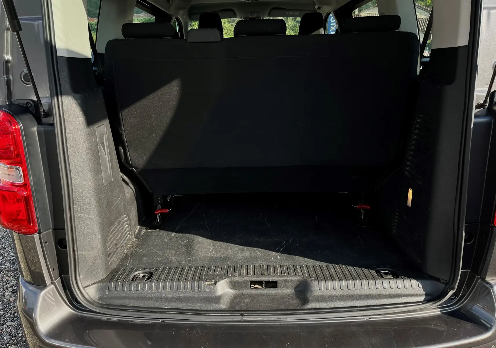 Coffre ouvert vu de l'arrière d'un Citroën Jumpy Spacetourer 2022 gris foncé, montrant la banquette arrière noire.