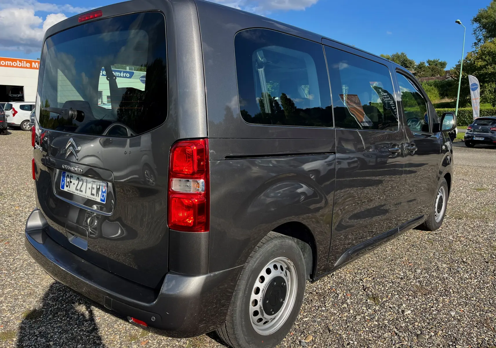 Vue 3/4 arrière droite d'un Citroën Jumpy Spacetourer gris foncé 2022 avec vitres teintées et jantes acier simples.