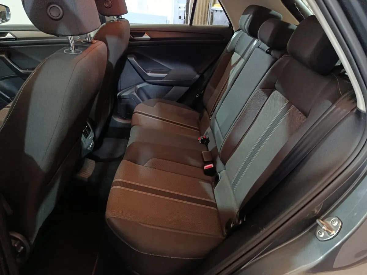 Vue intérieure côté droit sur la banquette arrière noire du Volkswagen T-Roc gris foncé, avec ceinture et appuie-têtes visibles.