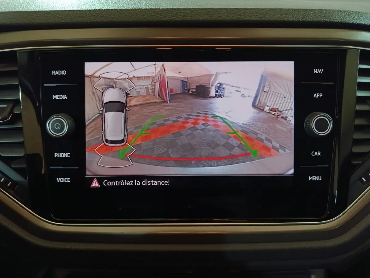 Écran tactile intérieur affichant la caméra de recul et l'aide au stationnement du Volkswagen T-Roc gris foncé.