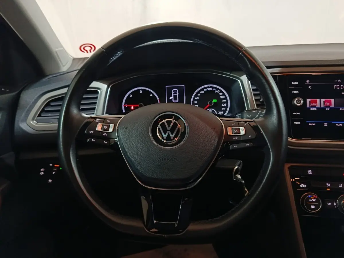 Vue rapprochée du volant cuir noir et du tableau de bord digital du Volkswagen T-Roc gris foncé 2021.